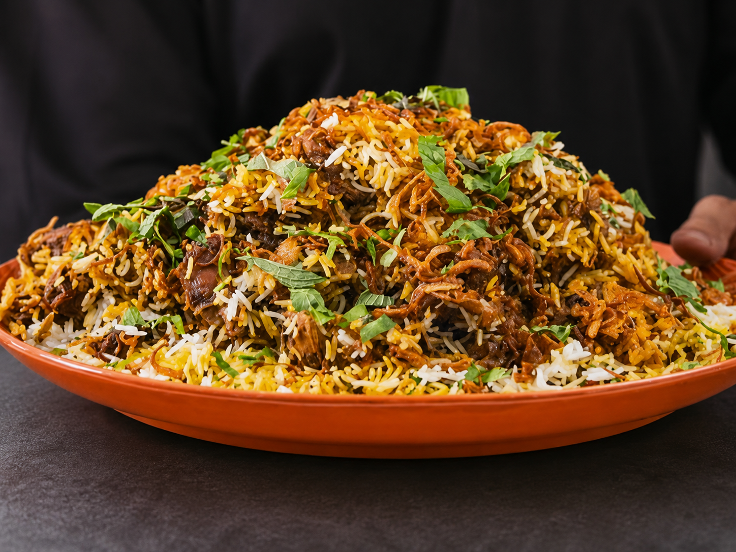 Large platter of coastal biryani garnished with herbs and fried onions.